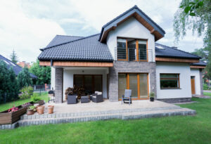 Rear exterior view of a modern two-story home with a patio and lawn, ideal for first-time buyers.