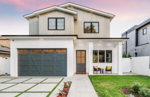 Exterior view of a modern two-story white and gray modern farmhouse with a wide garage and front porch.